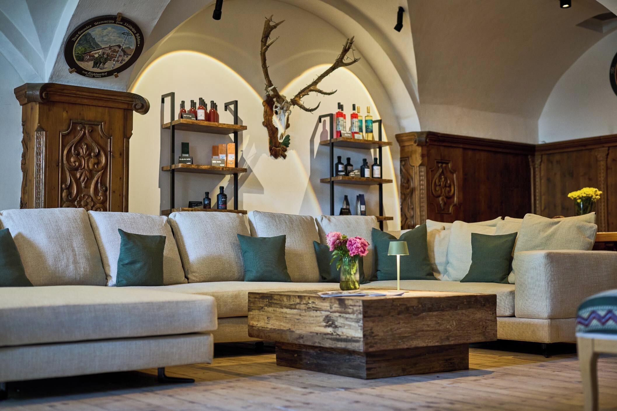 Ein gemütliches Wohnzimmer mit einer Eckcouch, einem Holztisch und dekorativen Regalen.