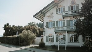 Een klassiek gebouw met een balkon, een bordje dat het een hotel identificeert, en een berg op de achtergrond.