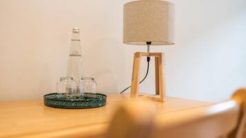 Une table sur laquelle se trouvent une bouteille, des verres et une lampe, le tout posé sur une surface en bois.