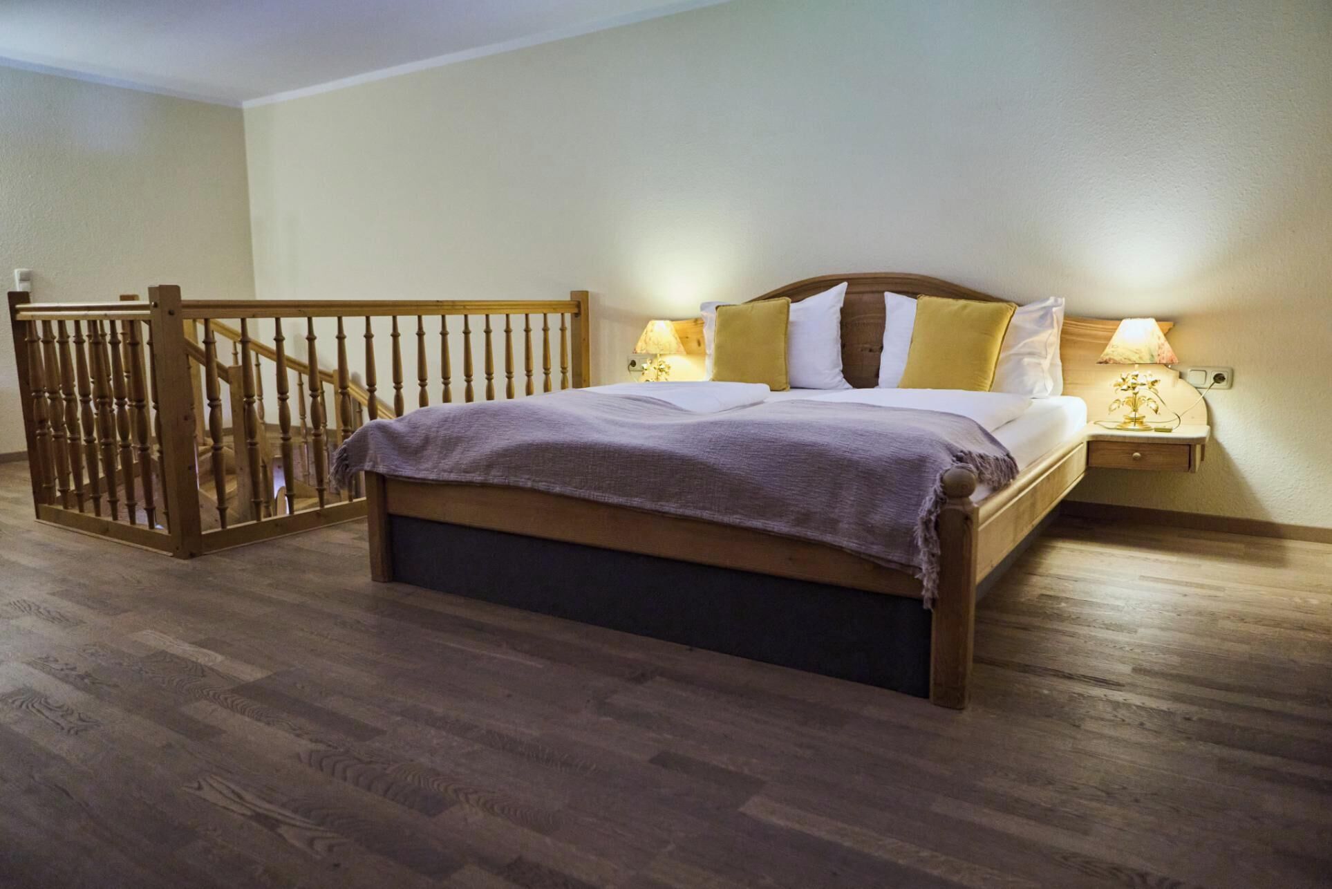 Un dormitorio con una cama de madera, una mesita de noche con una lámpara y un portón de madera.