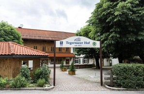 A traditional wooden building with a sign indicating it is a Tegernseer Hof since 1873. - Der Tegernseer Hof (Gmund am Tegernsee)