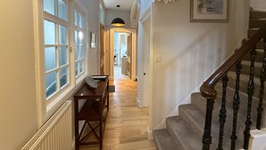 A hallway with a skylight, wooden flooring, a table, and a staircase. - Crown Circus Three Bedroom Apartment (Hillhead)
