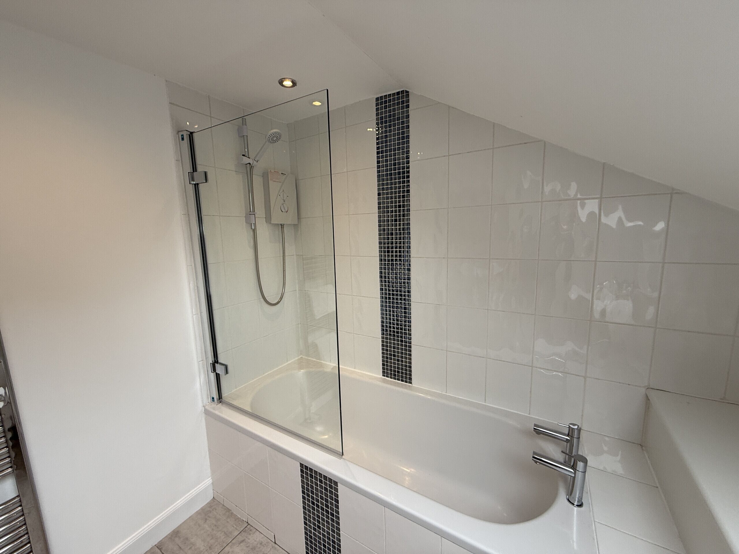 Een moderne badkamer met een douchecabine van glas, een vrijstaand bad en betegelde wanden.