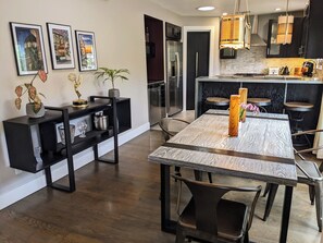 A modern kitchen with a central island, built-in appliances, and a dining area with a wooden table and chairs. - Pet-friendly Retreat in LA's Best Neighborhood (Los Angeles)