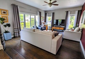 A living room with a sofa, armchairs, a TV, and a ceiling fan. - Pet-friendly Retreat in LA's Best Neighborhood (Los Angeles)