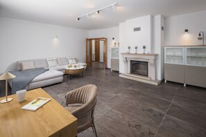 Un salon moderne comprenant un canapé, une table à manger, une cheminée et une bibliothèque.