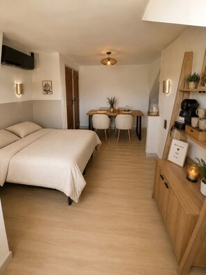 A compact hotel room with a bed, a dining table, chairs, a coffee machine, and a small cabinet. - Vrbo Property (Le Mans)