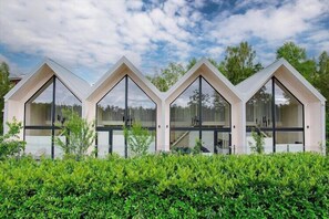 Une rangée de bâtiments modernes, dotés de toits triangulaires et de grandes fenêtres, avec un beau parterre bien entretenu au premier plan.