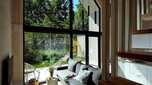 En modern inredning med stora fönster, en grå soffa och ett trägolv.