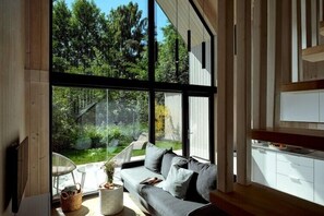 Un intérieur moderne avec de grandes fenêtres, un canapé gris et un plancher en bois.