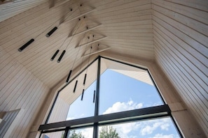 Une pièce avec un plafond en pente, de grandes fenêtres et des luminaires suspendus.