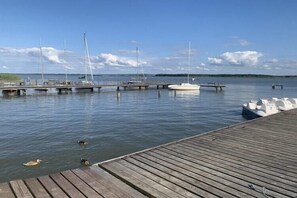 Une jetée en bois s’avançant dans une étendue d’eau calme, où plusieurs bateaux sont amarrés.