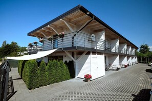 Een meerlaags gebouw met een balkon, een overdekt terras en een verharde looppad.