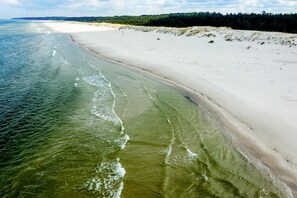 A beach with a sandy shore and a forest in the background. - Half of a holiday home with a large garden (Slajszewo)