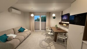 Un salon moderne comprenant un canapé, une table à manger, des chaises, un téléviseur à écran plat et un four à micro-ondes.