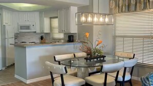 A modern kitchen with white cabinets, a central island with seating, and a pendant light fixture. - Luxury 3BR Resort Villa w/ Jacuzzi Near Disney (Kissimmee)