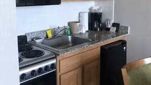 A kitchen with wooden cabinets, a microwave, a stove, a refrigerator, and a coffee maker. - Barclay Towers Suites 1442M (Virginia Beach)