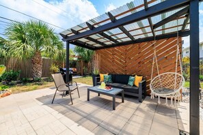 Eine Terrasse im Freien mit überdachter Sitzecke, einem Tisch und einem Hängestuhl.