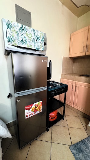 A kitchen with a stainless steel refrigerator, a gas stove, and a tiled floor. - Studio in south b near airport (Nairobi)