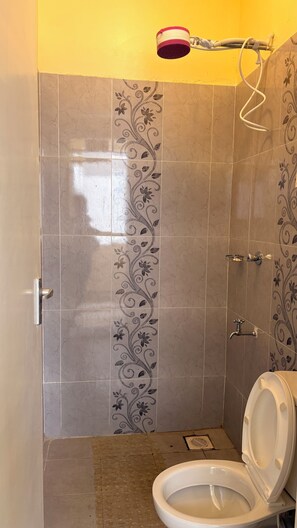 Un baño con ducha, inodoro y azulejos decorativos.