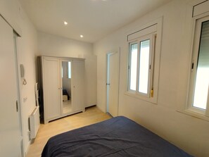 A bedroom with a bed, a wardrobe, a mirror, and a window. - Apartment in Barcelona near the Boqueria Market (Las Ramblas) (Barcelona)