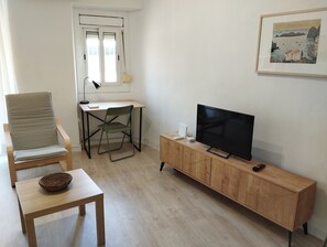 A living room with a TV, a chair, a small table, and a cabinet. - Apartment in Barcelona near the Boqueria Market (Las Ramblas) (Barcelona)