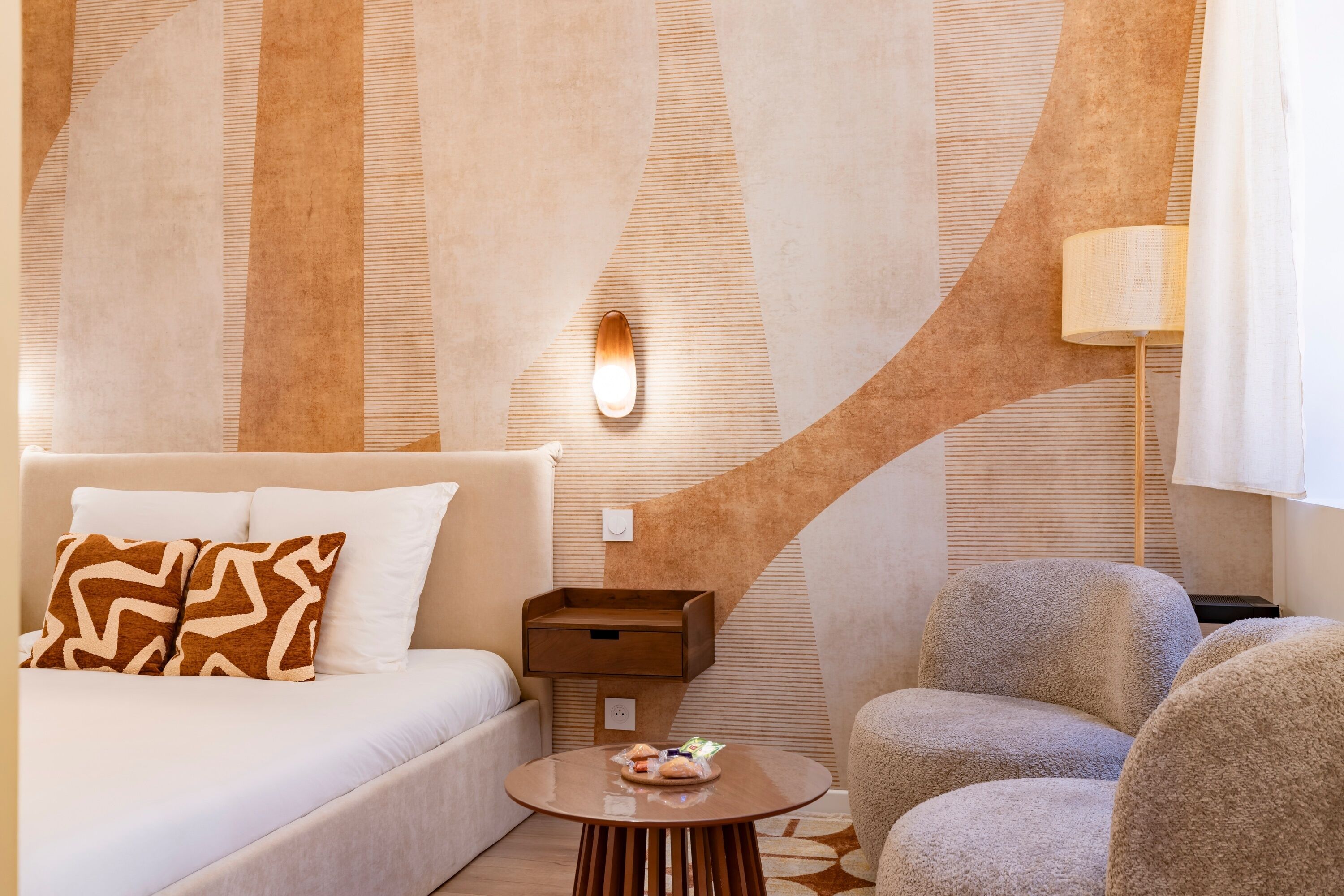 A hotel room with a bed, a round coffee table, a sofa, and a lamp.