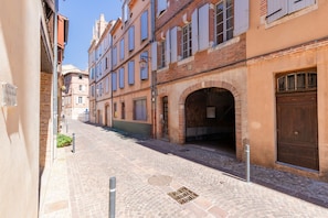A narrow cobblestone street lined with historic buildings, featuring a brick archway and a wooden door. - Studio Balnéo - L'Idylle Albigeoise - Appt pour 2 en centre-ville (Albi)