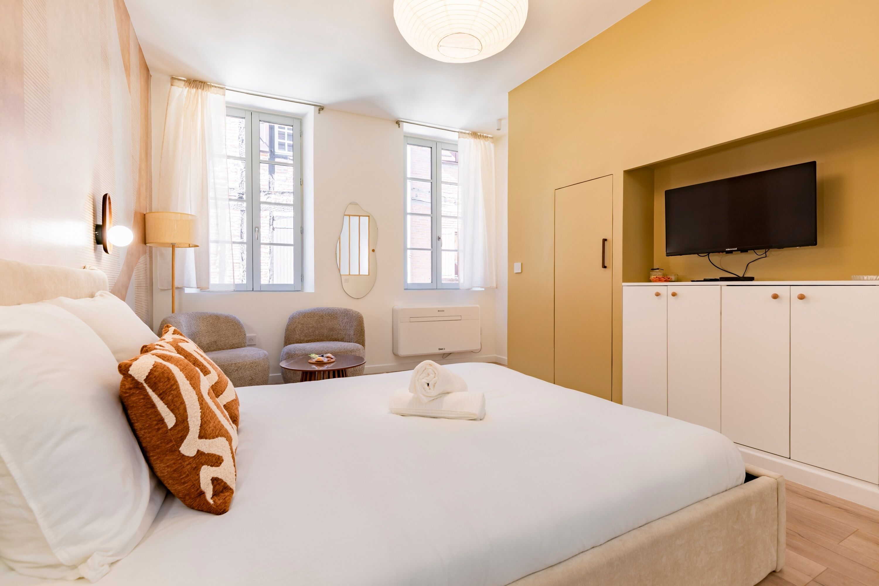 Una camera d'albergo con un letto, una televisione, una sedia, una lampada e una finestra.