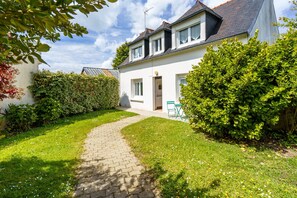 A two-story house with a paved pathway leading to the entrance, surrounded by lush greenery and a clear sky. - Ty Cos-Ker - Dans le bourg de Crozon (Crozon)