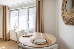 Ein Essbereich mit einem runden Tisch, Stühlen und einem Fenster mit Vorhängen.