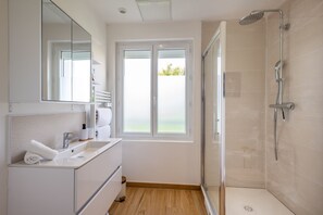 Ein modernes Badezimmer mit Dusche, Waschbecken, Spiegel und Fenster.