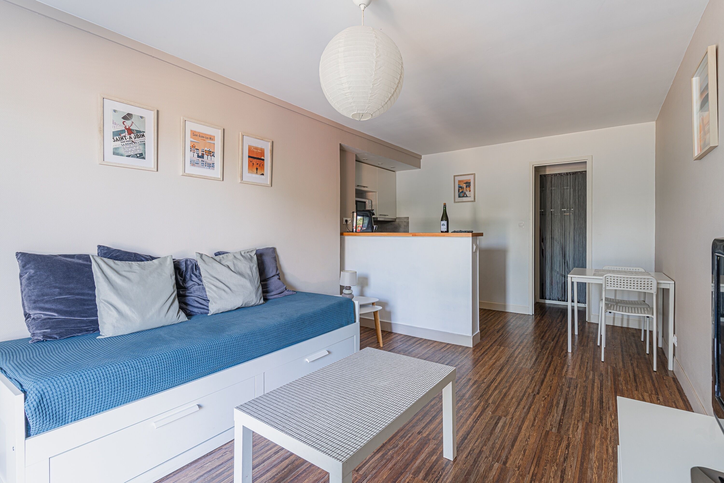 A compact living space with a sofa, a small table, a kitchenette, and a dining area.