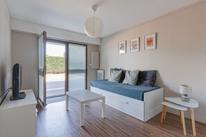 A modern room with a bed, a desk, a chair, and a door leading outside. - La Pause courseullaise - Joli studio proche plage (Courseulles-sur-Mer)