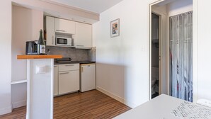 Et kompakt køkken med en mikrobølgeovn, et lille køleskab og en træbordplade.