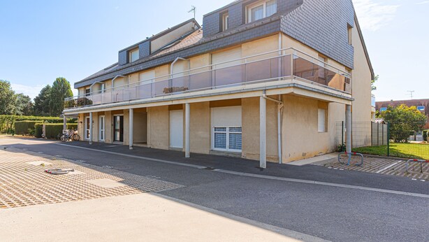 En toetages boligbygning med balkon, garage og indkørsel.