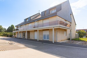 A two-story residential building with a balcony, a garage, and a driveway. - La Pause courseullaise - Joli studio proche plage (Courseulles-sur-Mer)