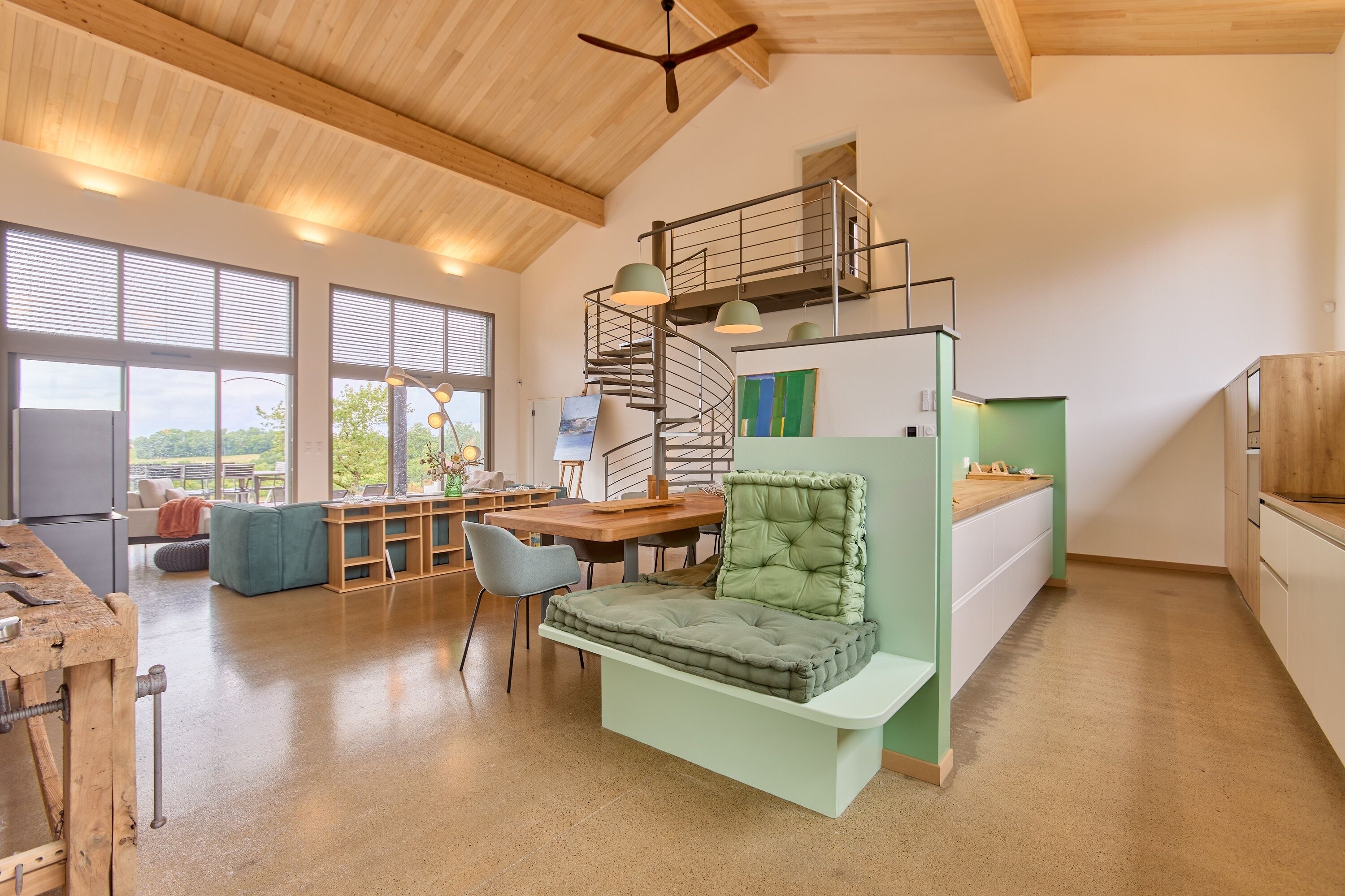 A modern interior with a loft-style bed, a dining area, and a workspace.