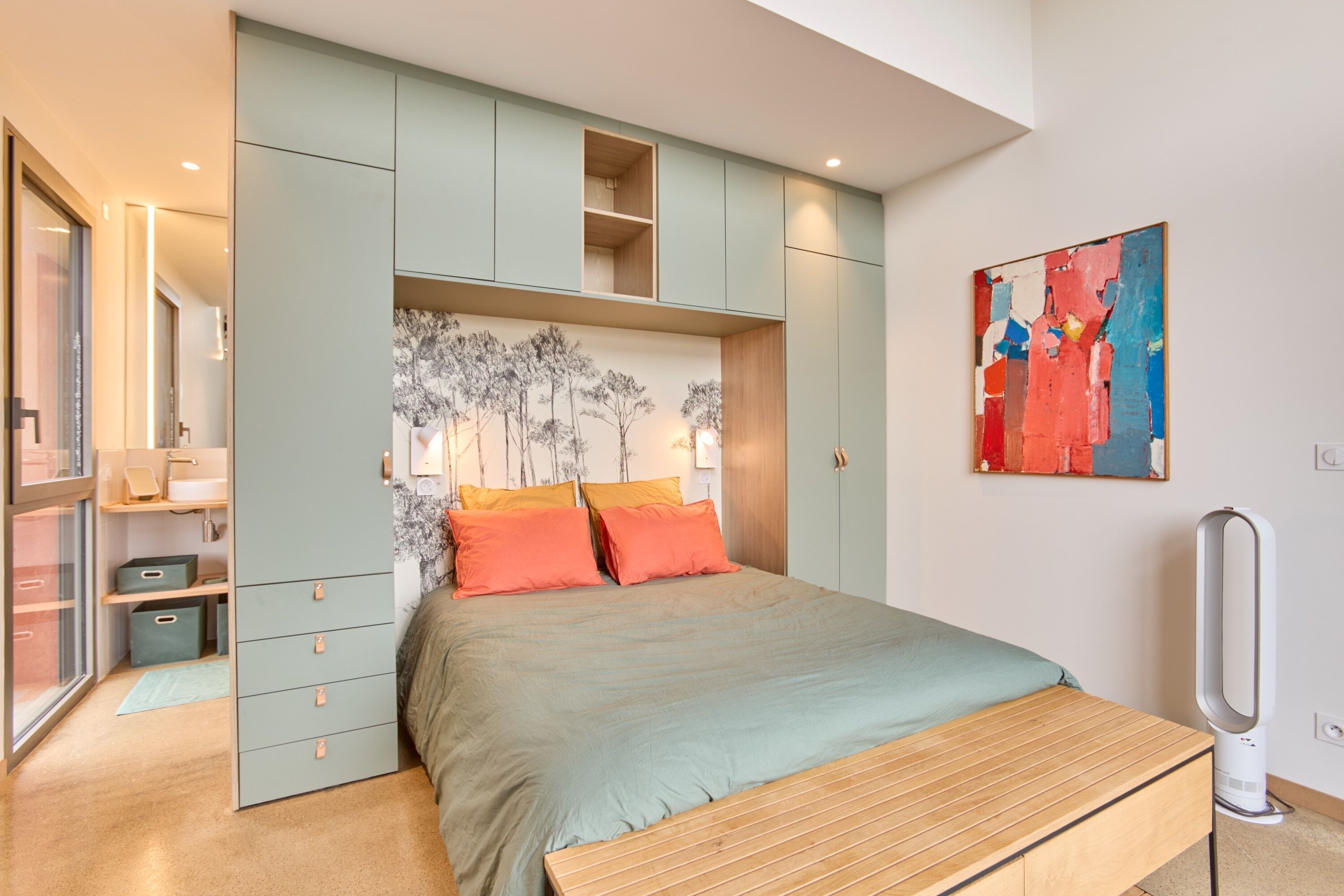 A bedroom with a bed, built-in storage, a bedside table, and a wall-mounted artwork.