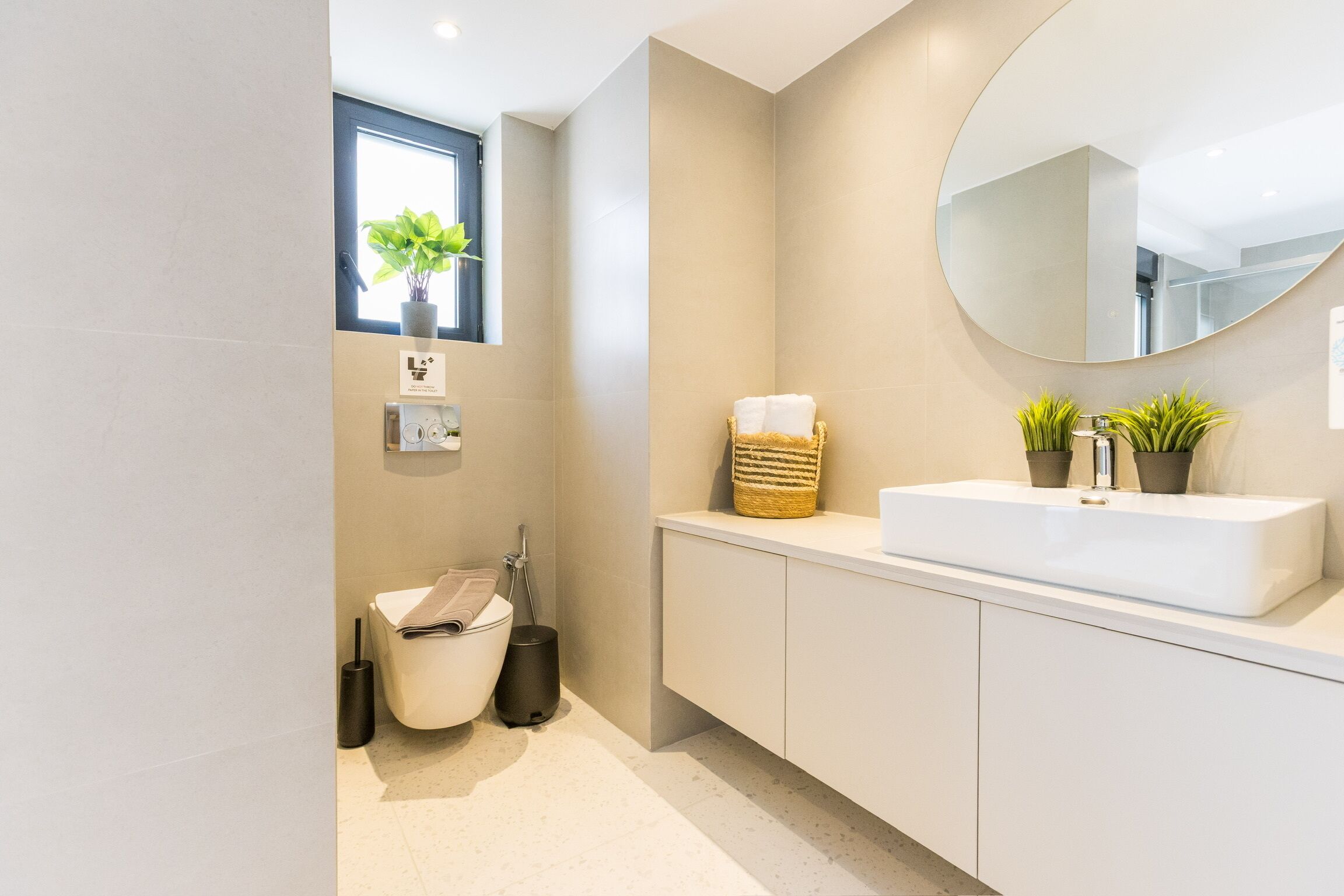 Ein modernes Badezimmer mit Toilette, Bidet, Waschbecken und einem großen Spiegel.