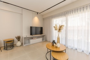 A modern living room with a flat-screen TV, a round wooden table, and a white console. - B Boutique Residences by Raise (Athens)