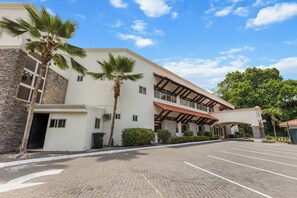 Ein Hotel mit Stein-Fassade, überdachter Eingangspartie und Parkplatz.