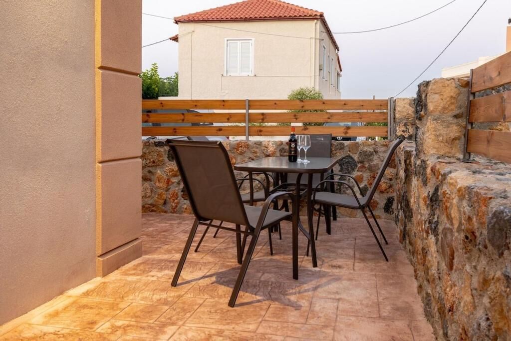 A patio with a table and chairs, a bottle of wine, and a glass.
