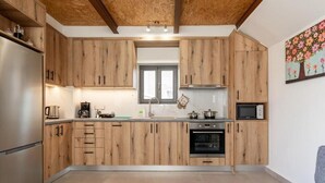 A modern kitchen with wooden cabinets, a built-in oven, and a microwave. - Villa Elpida (Chania)