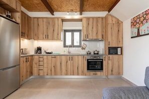 A modern kitchen with wooden cabinets, a built-in oven, and a microwave. - Villa Elpida (Chania)