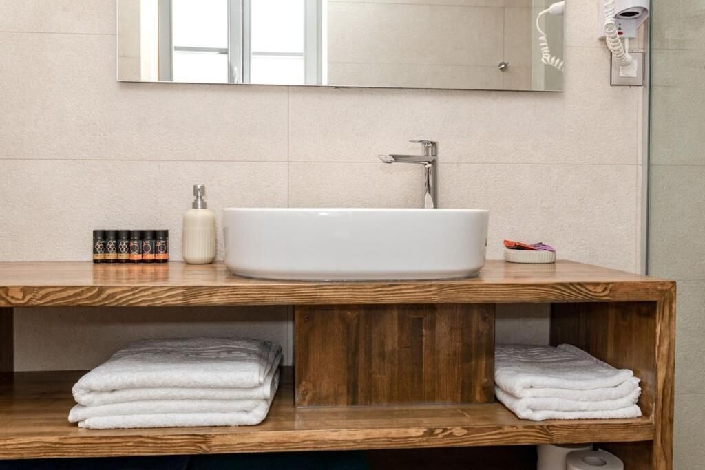 A bathroom with a wooden vanity, a white sink, and a mirror above it.
