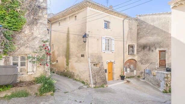 A narrow street with a building featuring a small window, a door, and a lamp post. - La Sacristie - Au coeur du village de Donzère (Donzère)