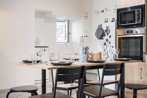 Una cucina moderna con tavolo da pranzo per quattro persone, forno a microonde, forno e frigorifero.