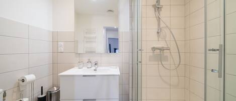 A modern bathroom with a glass-enclosed shower, a white vanity, and a toilet.