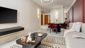 Ein modernes Wohnzimmer mit Flachbildfernseher, einem Essbereich mit roten Stühlen und einer Couch.